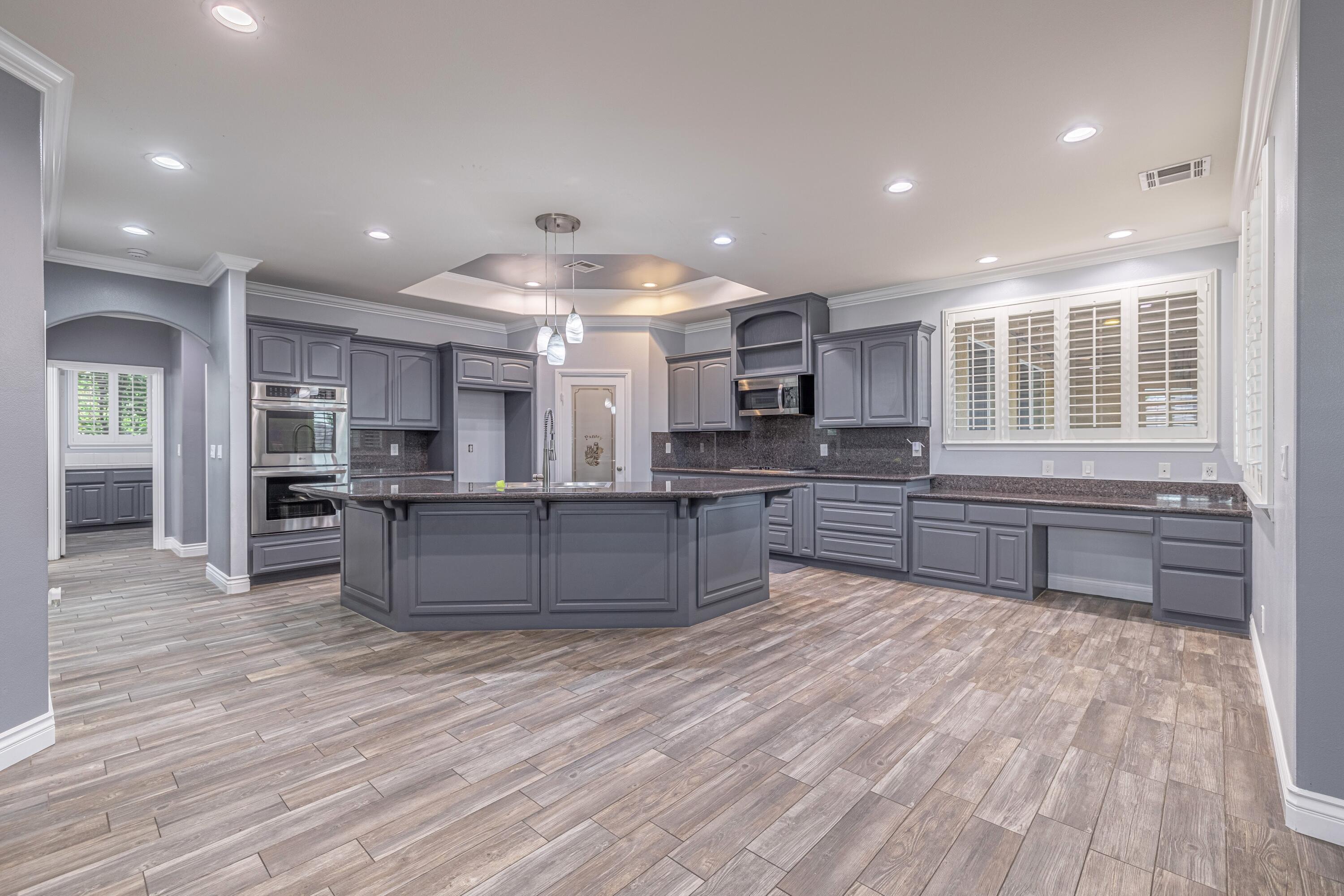 4023 Derby Circle Lancaster, CA 93536 - Photo 3 of 53 a large kitchen with stainless steel appliances kitchen island granite countertop a large counter top and wooden floors