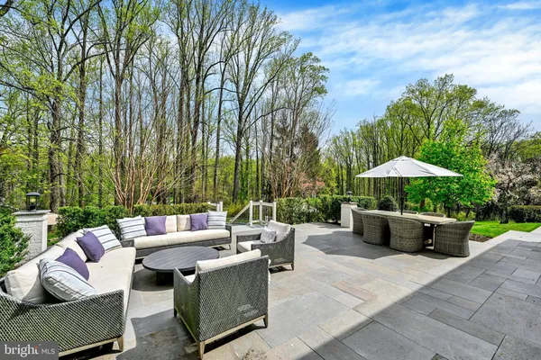a view of a patio with couches table and chairs under an umbrella with a fire pit