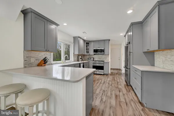a kitchen with stainless steel appliances granite countertop a kitchen island hardwood floor sink and stove