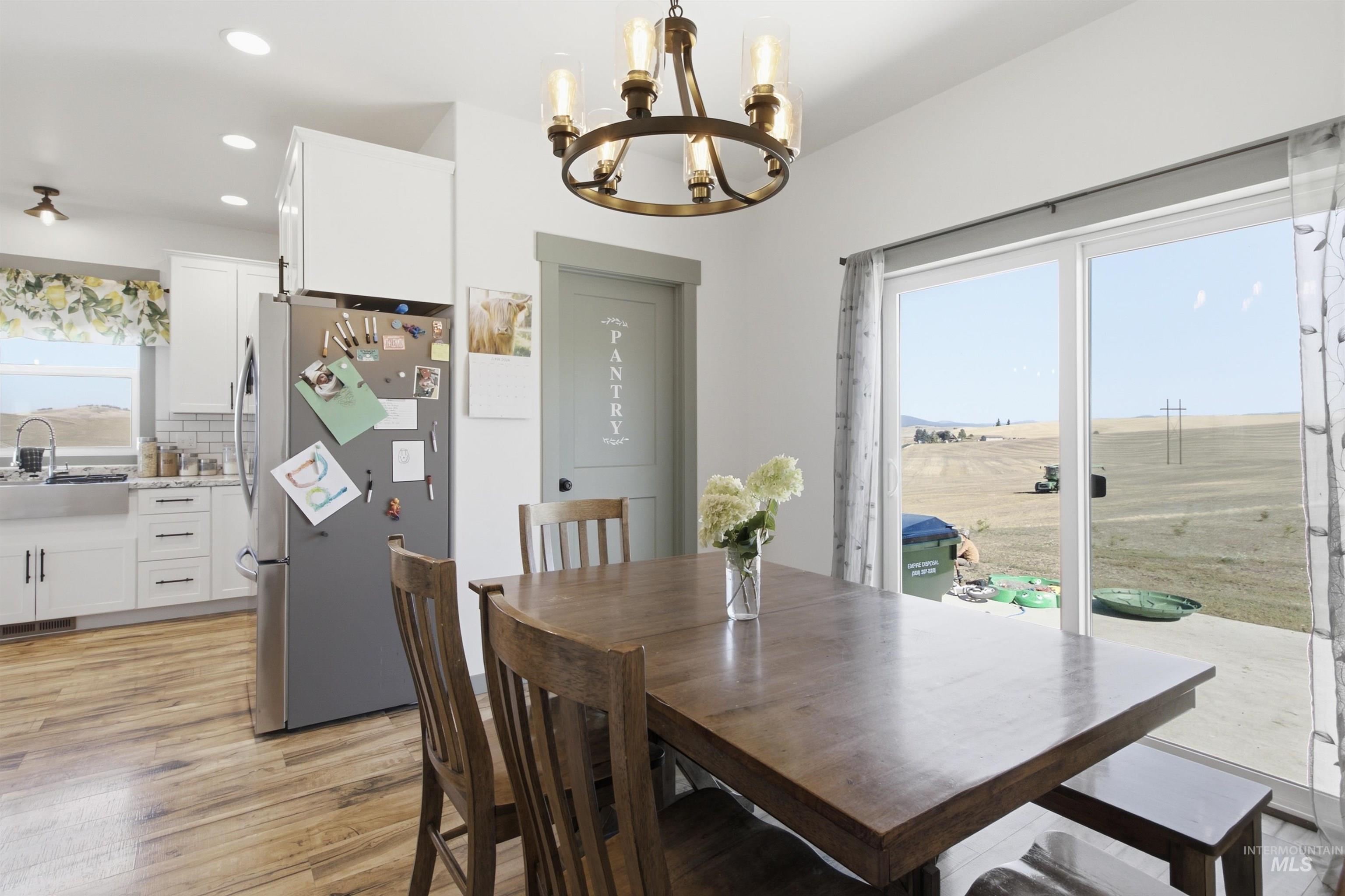 1032 Duffield Flat Road Potlatch, ID 83855 - Photo 13 of 50 Wood-finish flooring, white cabinetry, stainless steel refrigerator, white subway tile backsplash, and sliding glass patio doors