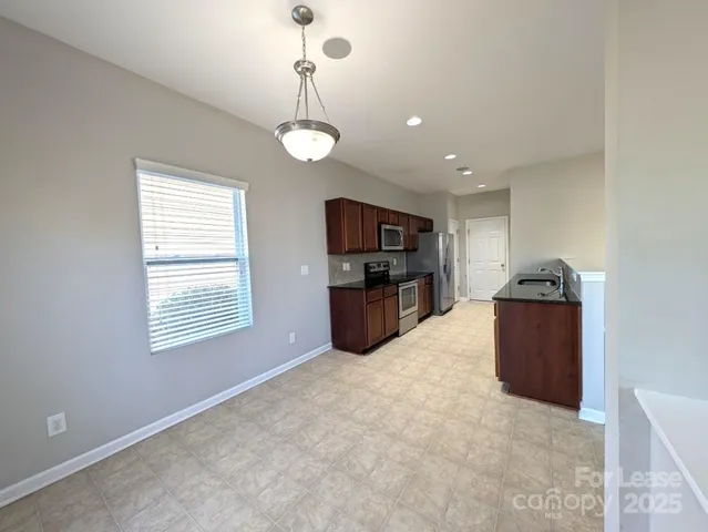 a kitchen with stainless steel appliances granite countertop a refrigerator and a wooden floors