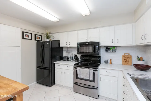 a kitchen with stainless steel appliances a refrigerator stove and white cabinets