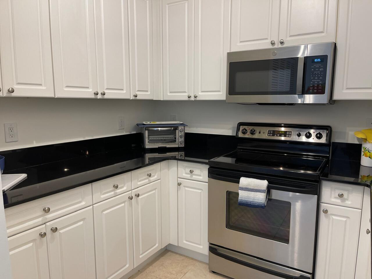 255 Evernia Street, Unit 407 West Palm Beach, FL 33401 - Photo 14 of 31 a kitchen with stainless steel appliances granite countertop white cabinets and a stove a oven