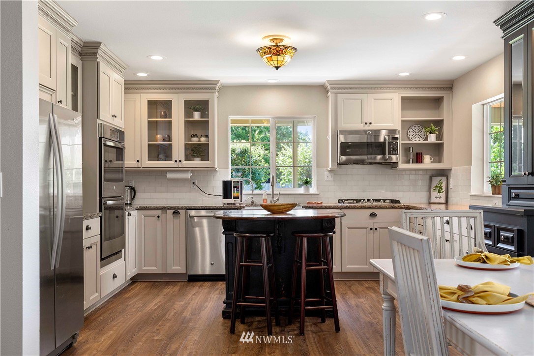 9451 Avon Allen Road Bow, WA 98232 - Photo 12 of 40 a kitchen with stainless steel appliances granite countertop a stove a refrigerator and a dining table with wooden floor