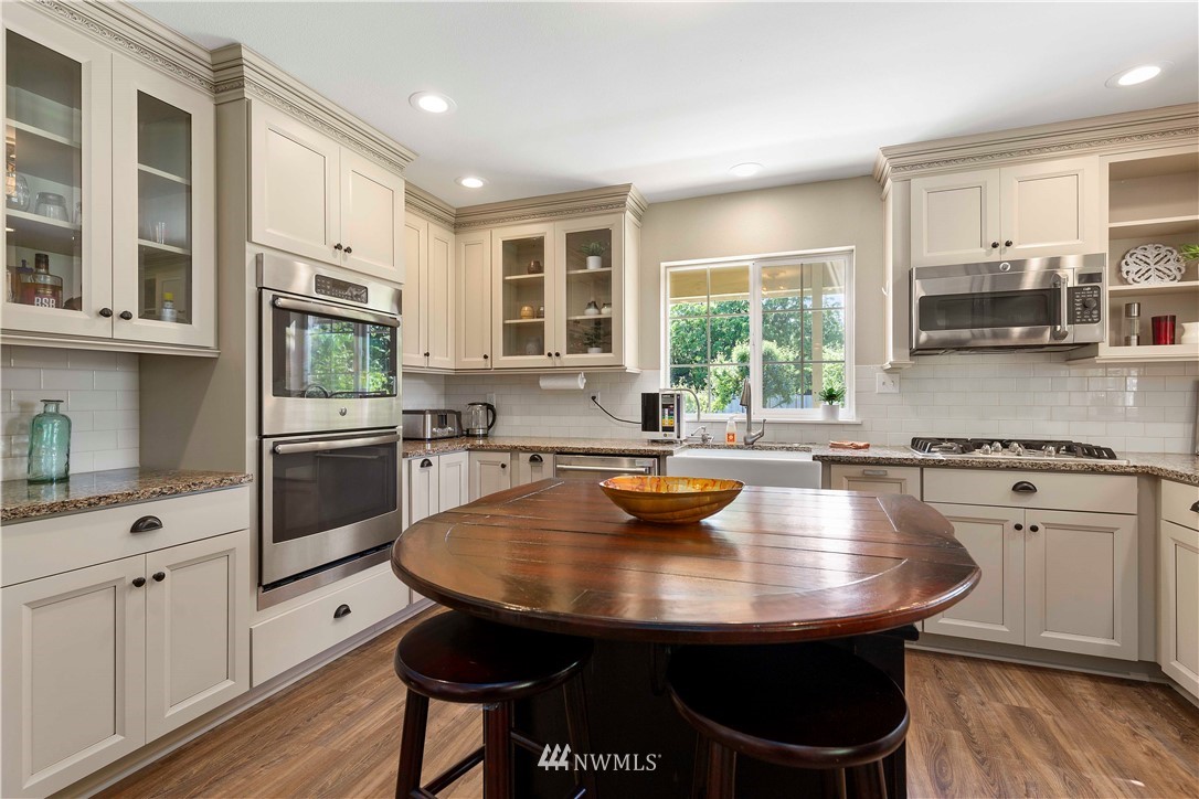9451 Avon Allen Road Bow, WA 98232 - Photo 14 of 40 a kitchen with stainless steel appliances kitchen island granite countertop a sink a stove and white cabinets with wooden floor