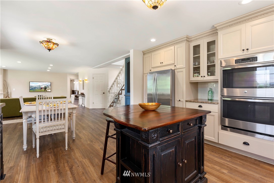 9451 Avon Allen Road Bow, WA 98232 - Photo 15 of 40 a kitchen with a stove a refrigerator and a dining table with wooden floor