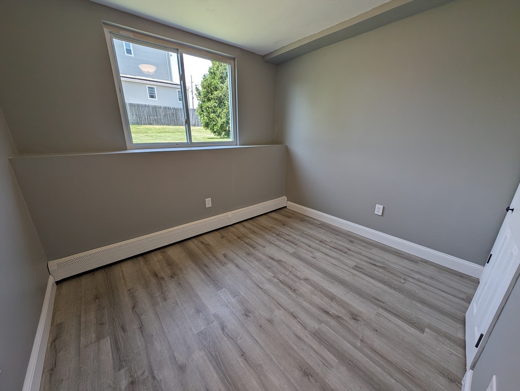 191 Glasgow Street, Unit 3 Fall River, MA 02721 - Photo 7 of 16 an empty room with wooden floor and windows