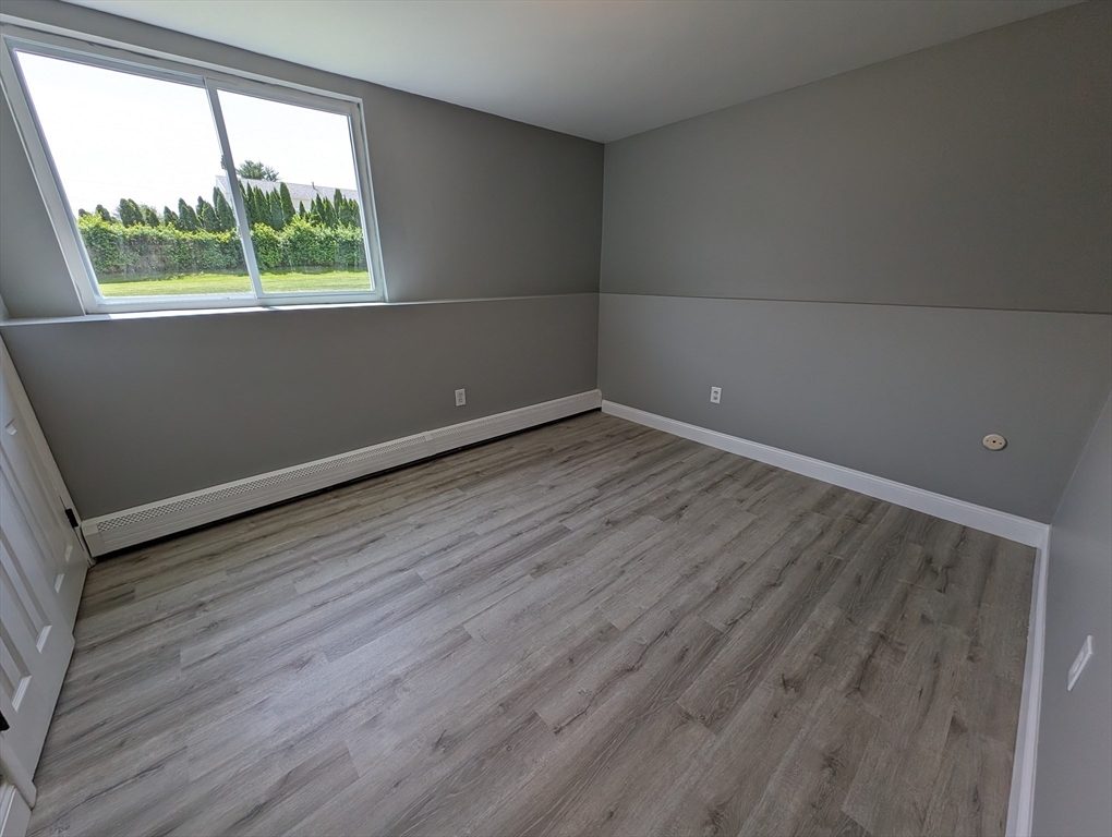 191 Glasgow Street, Unit 3 Fall River, MA 02721 - Photo 9 of 16 an empty room with wooden floor and windows