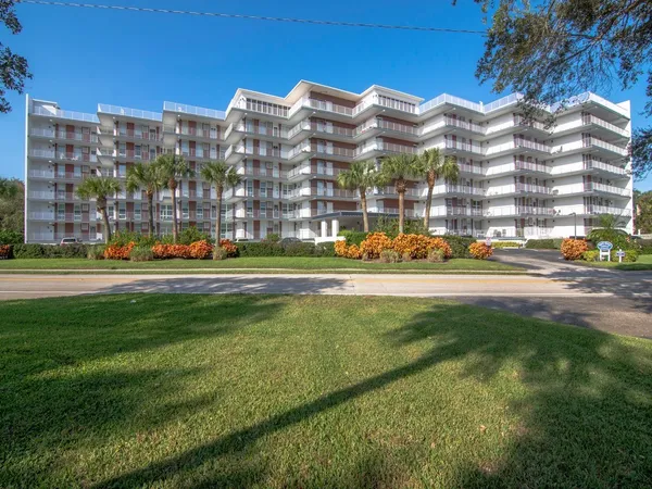 a view of a building with a yard and trees in the background