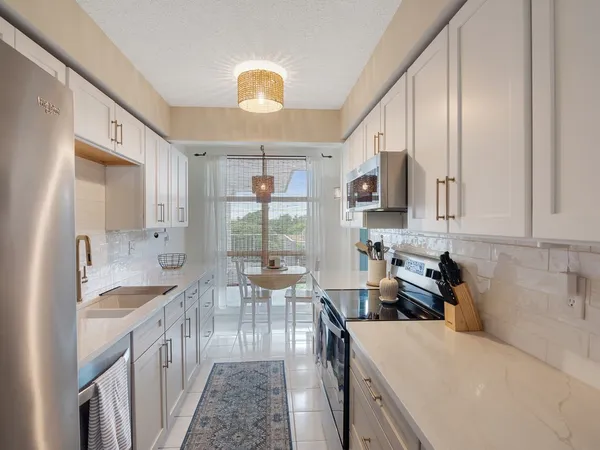 a kitchen with stainless steel appliances granite countertop a sink dishwasher stove refrigerator and cabinets