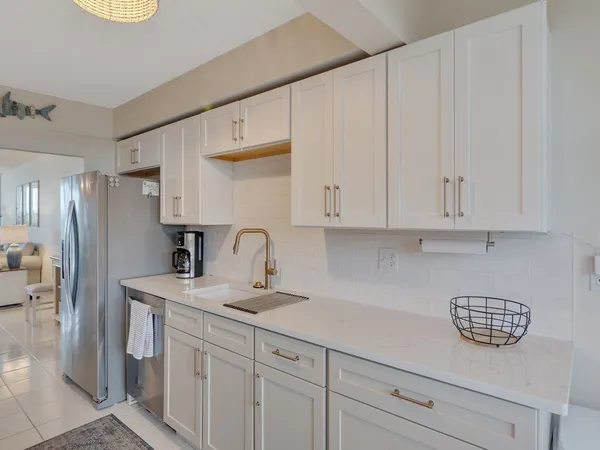 a kitchen with stainless steel appliances granite countertop a sink a refrigerator and white cabinets