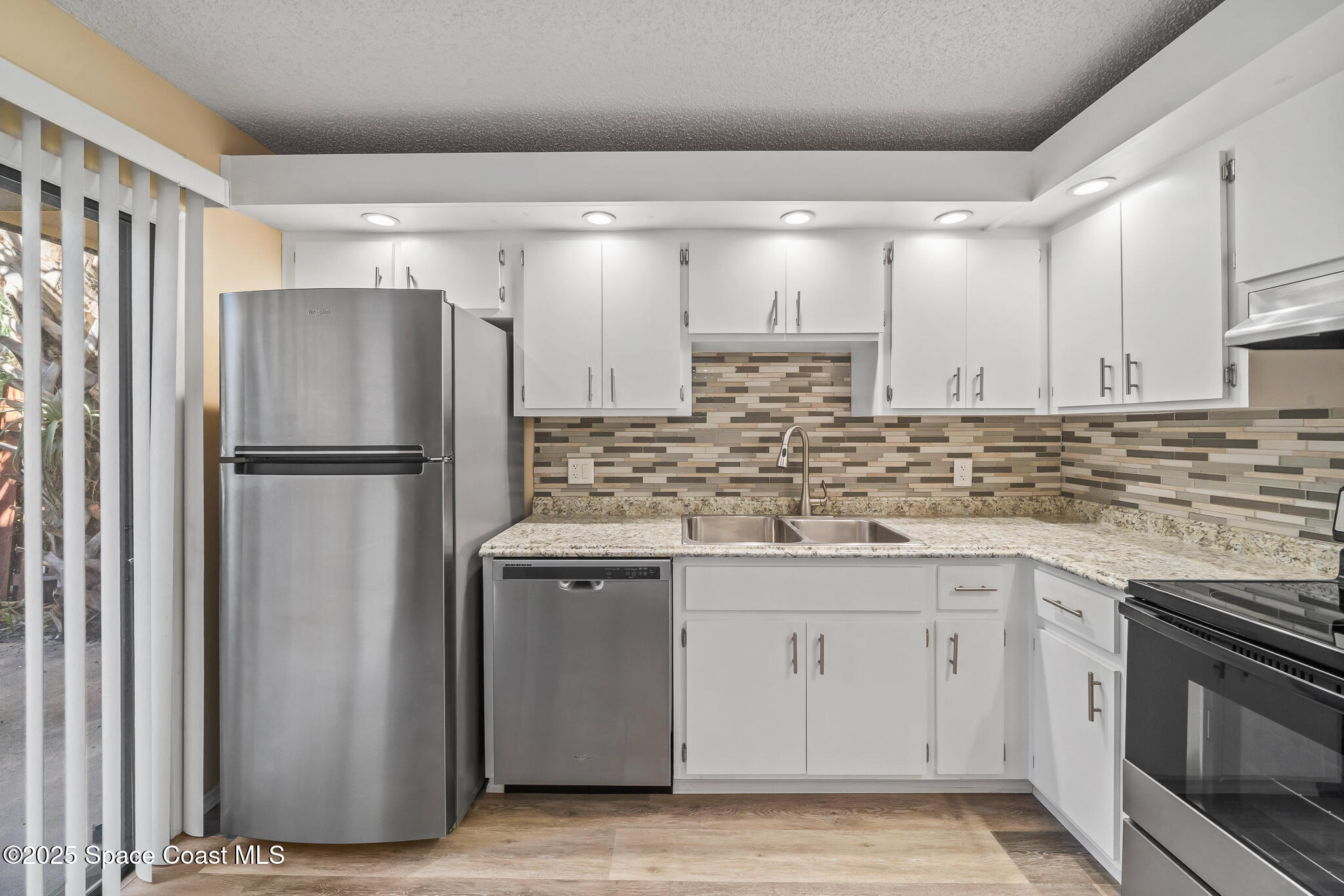 1713 Patty Circle Northeast Palm Bay, FL 32905 - Photo 15 of 26 a kitchen with stainless steel appliances granite countertop a refrigerator a sink and white cabinets