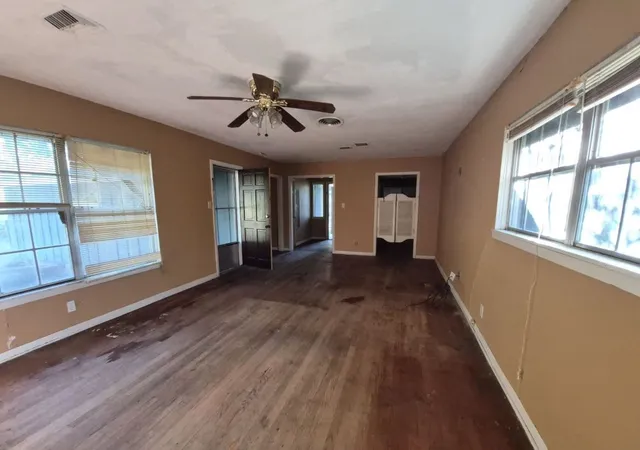 a view of empty room with wooden floor and fan