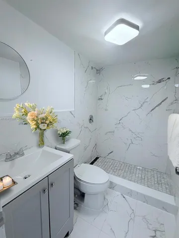 a white toilet sitting next to a bathroom sink and a mirror