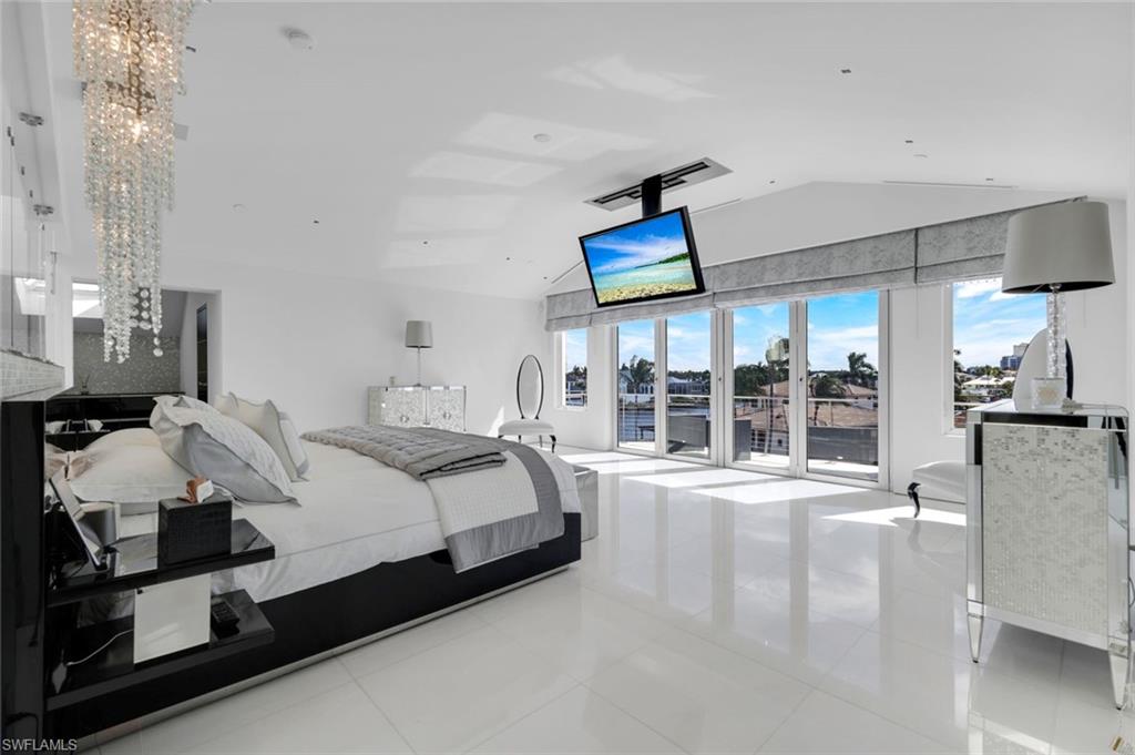 260 Channel Drive Naples, FL 34108 - Photo 16 of 48 a spacious bedroom with a bed a large window and mirror