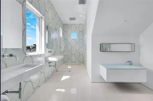 a bedroom with a bed a chair and three windows