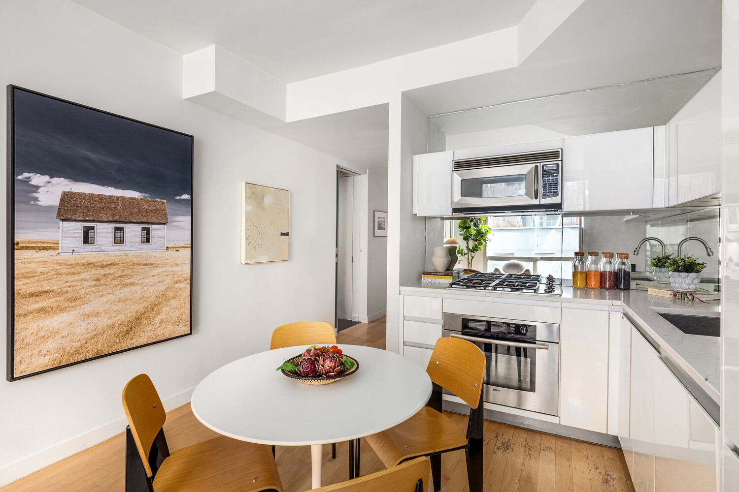 425 East 13th Street, Unit 2B Manhattan, NY 10009 - Photo 4 of 17 a kitchen with stainless steel appliances granite countertop a dining table and chairs with wooden floor