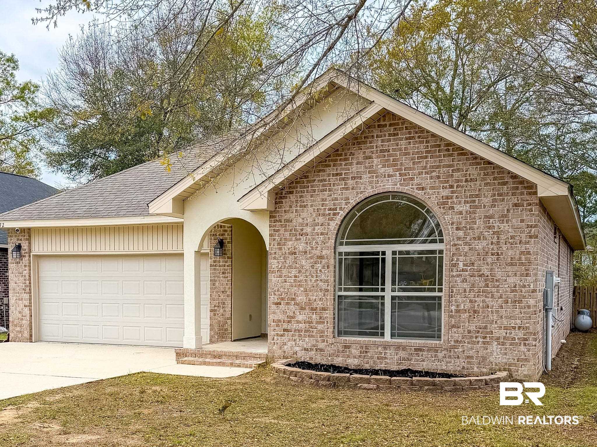 7332 Raintree Lane Gulf Shores, AL 36542 - Photo 2 of 21 View of front of property featuring brick siding, a shingled roof, an attached garage, concrete driveway, and a front yard