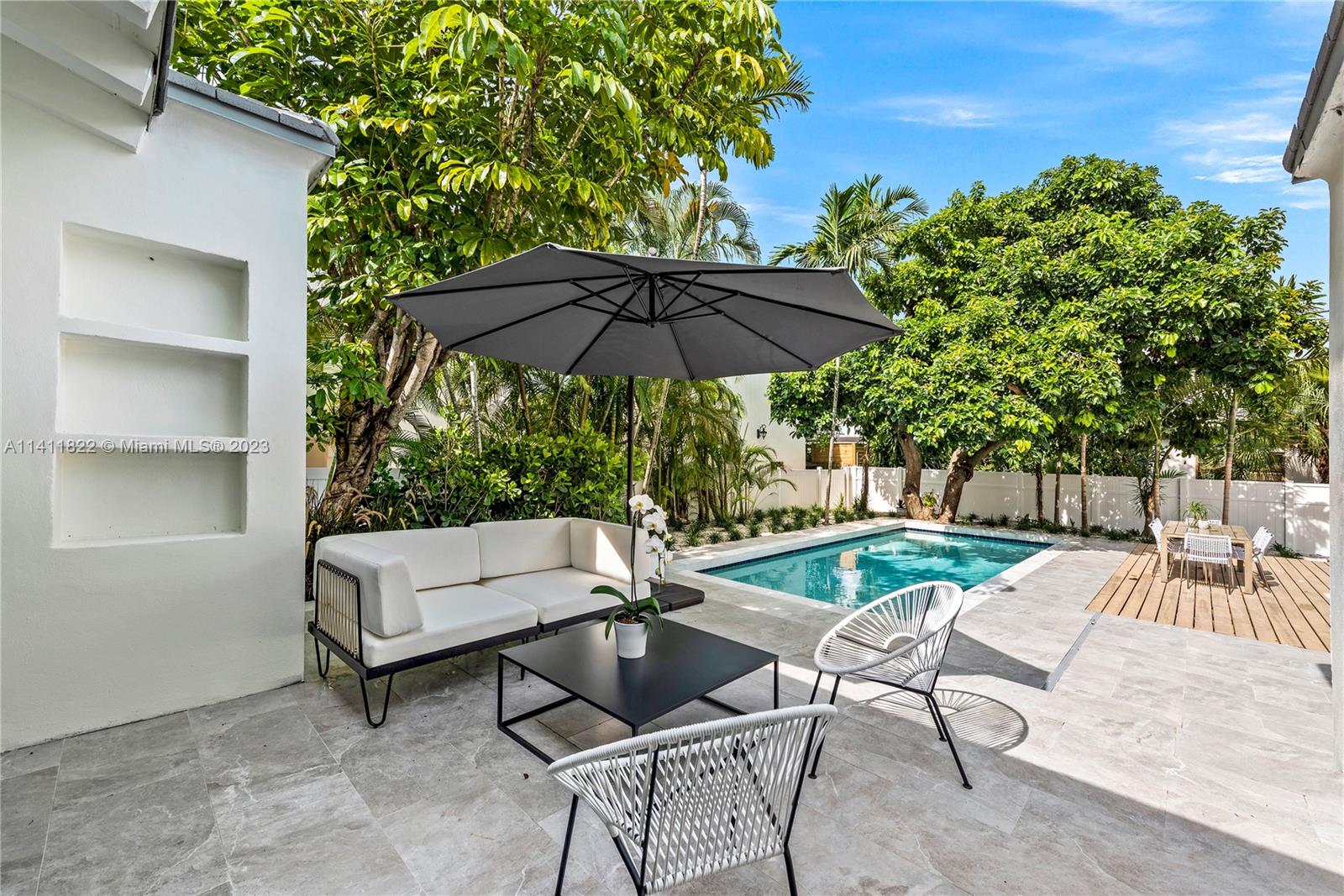 5956 Pine Tree Drive Miami Beach, FL 33140 - Photo 14 of 55 a view of patio with chairs and table under an umbrella with a barbeque