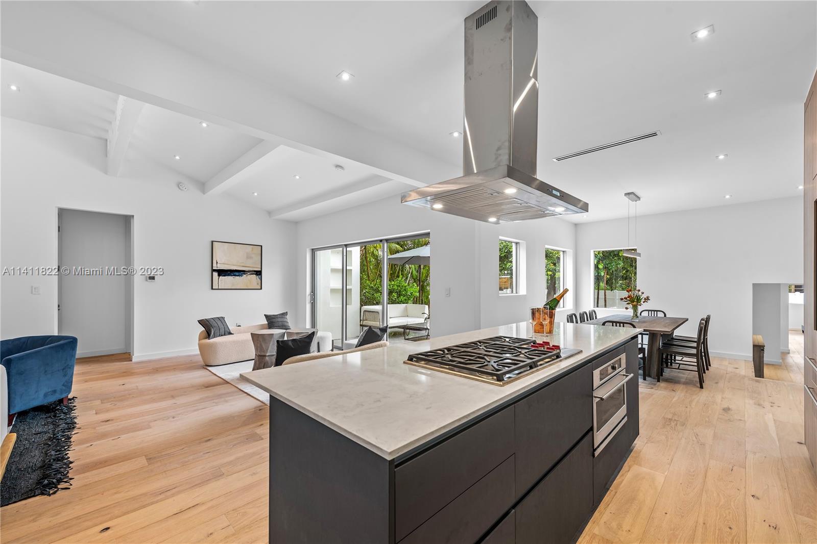 5956 Pine Tree Drive Miami Beach, FL 33140 - Photo 9 of 55 a kitchen with a stove a sink dishwasher and a dining table with wooden floor