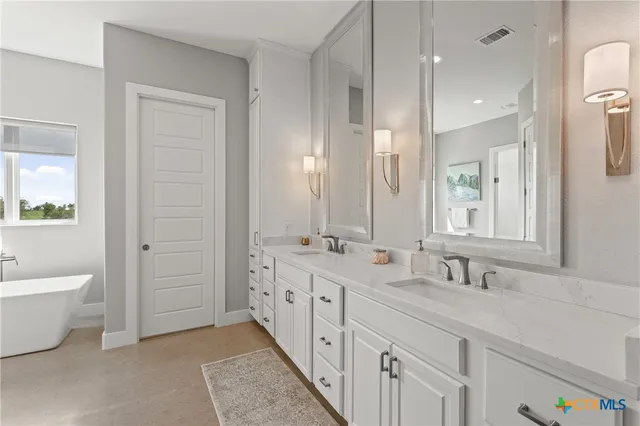 a bathroom with double vanity sinks a toilet a mirror and a bathtub