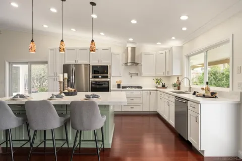 a kitchen with stainless steel appliances kitchen island granite countertop a table chairs and a refrigerator