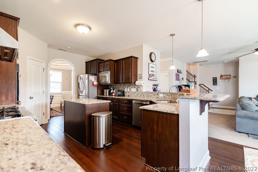 335 Turriff Way Cameron, NC 28326 - Photo 19 of 50 a kitchen with kitchen island granite countertop wooden floors and stainless steel appliances
