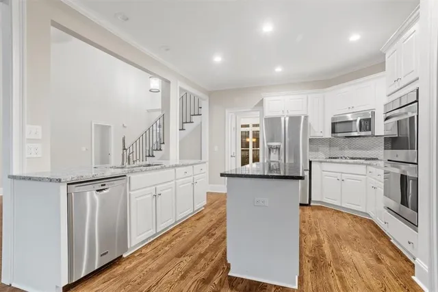 a kitchen with granite countertop white cabinets and stainless steel appliances