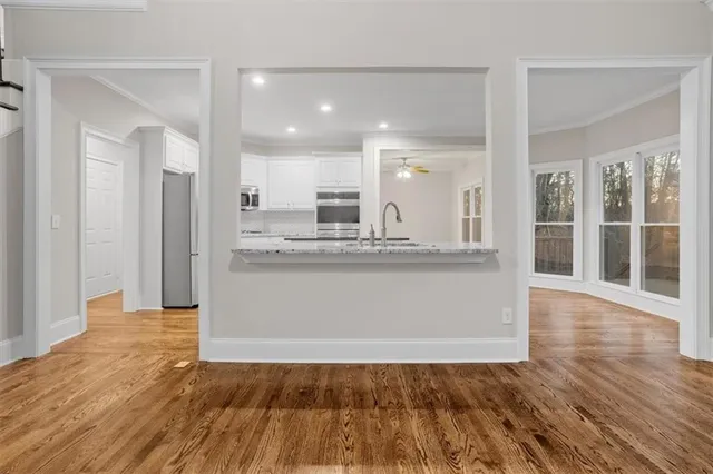 a view of an empty room with kitchen and a window