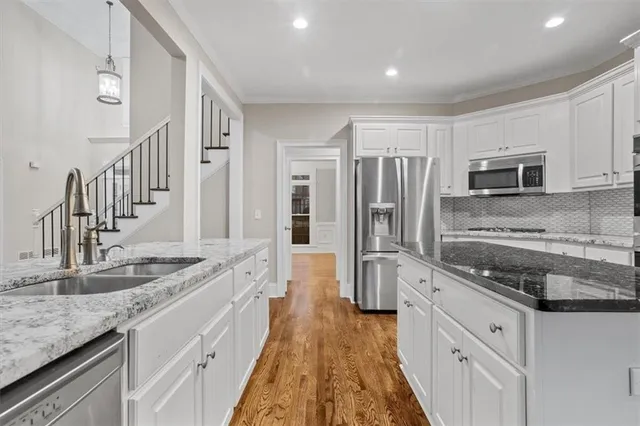 a large kitchen with granite countertop a stove top oven a sink a dining table and chairs