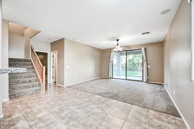 a view of an empty room with stairs and a window