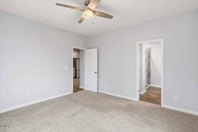 a view of an empty room and chandelier fan