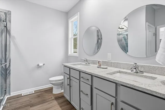 a bathroom with a granite countertop toilet a sink and a mirror