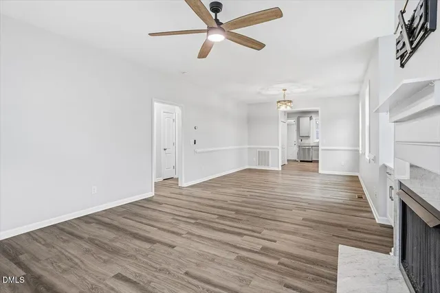 a view of empty room with wooden floor and ceiling fan