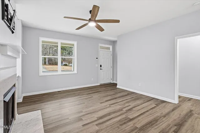 a view of a livingroom with wooden floor a ceiling fan and a window