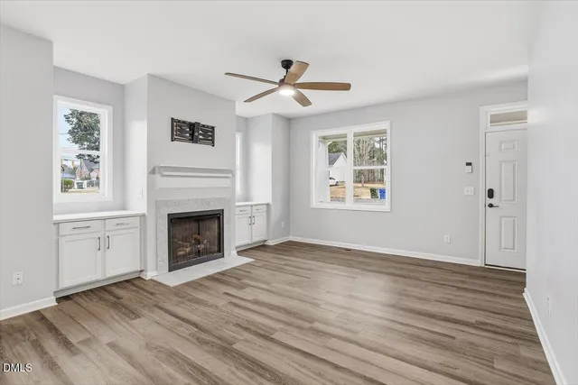 an empty room with windows fireplace and wooden floor