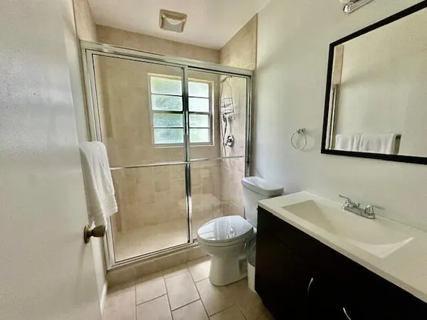 a bathroom with a shower sink vanity and toilet