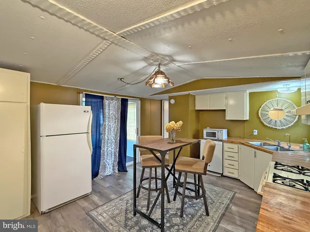 a kitchen with stainless steel appliances granite countertop a table chairs in it and a window