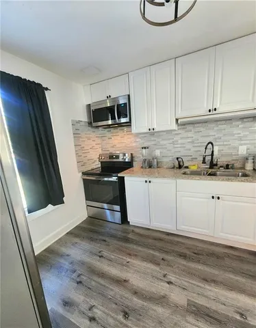 a kitchen with stainless steel appliances granite countertop a sink a stove a microwave and cabinets