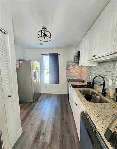 a kitchen with granite countertop stainless steel appliances a sink window and cabinets