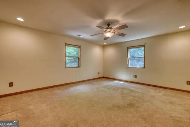 an empty room with chandelier fan and windows