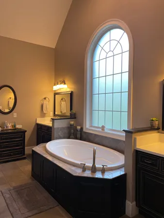 a bathroom with a tub a sink and a large window