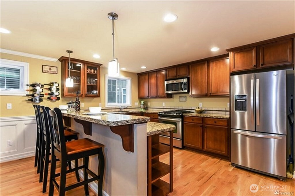 725 North 95th Street, Unit C Seattle, WA 98103 - Photo 6 of 18 a kitchen with stainless steel appliances granite countertop a stove top oven a refrigerator a sink and chairs