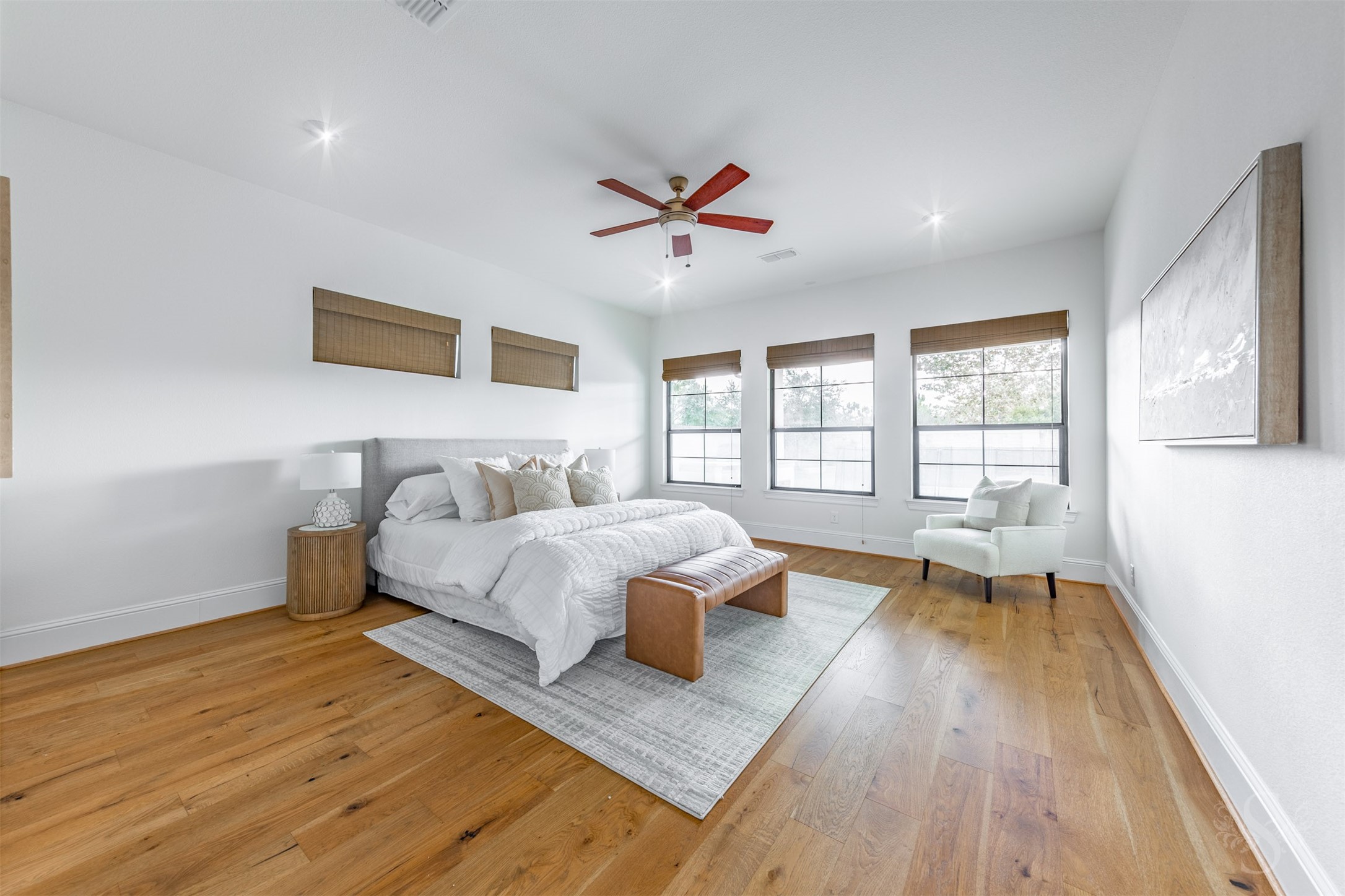 27919 Indigo Ridge Drive Fulshear, TX 77441 - Photo 25 of 50 The serene primary bedroom offers an expansive layout with warm wood flooring, soft natural light, and plenty of space for a sitting area or reading nook. Multiple large windows create a bright, calming retreat that feels both inviting and luxurious.