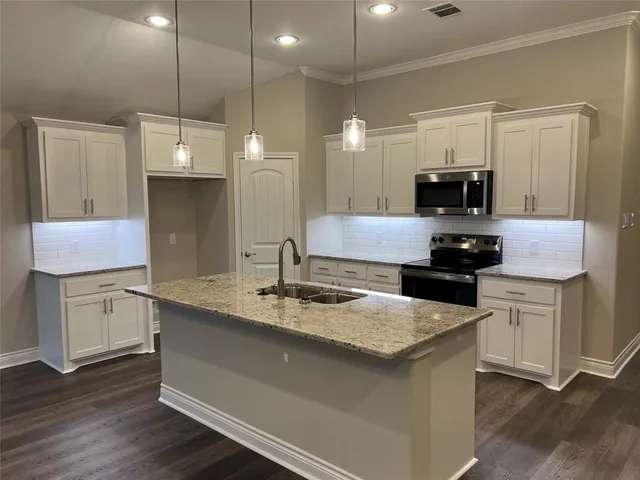 a kitchen with granite countertop a sink a counter top space appliances and cabinets
