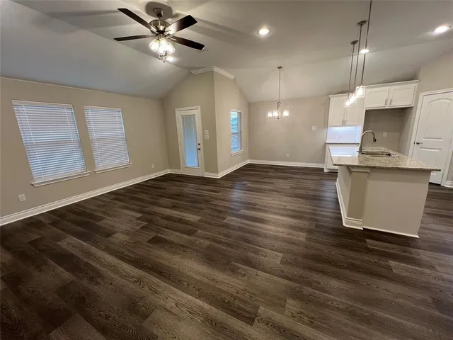 a view of kitchen and empty room with wooden floor