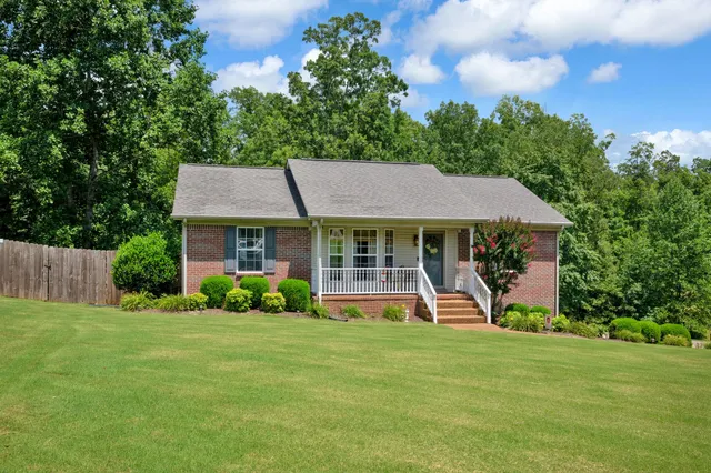 a front view of a house with a garden and trees