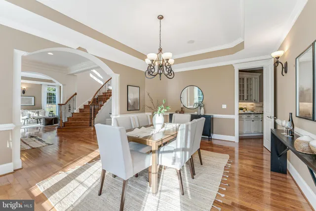 a kitchen with stainless steel appliances a stove a sink dishwasher a refrigerator and a dining table with wooden floor