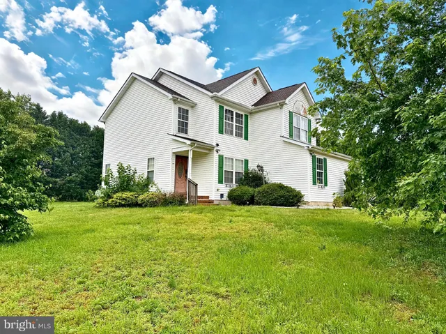 a view of a house with a big yard and large trees