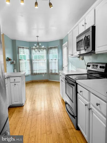a kitchen with stainless steel appliances wooden floors and view living room